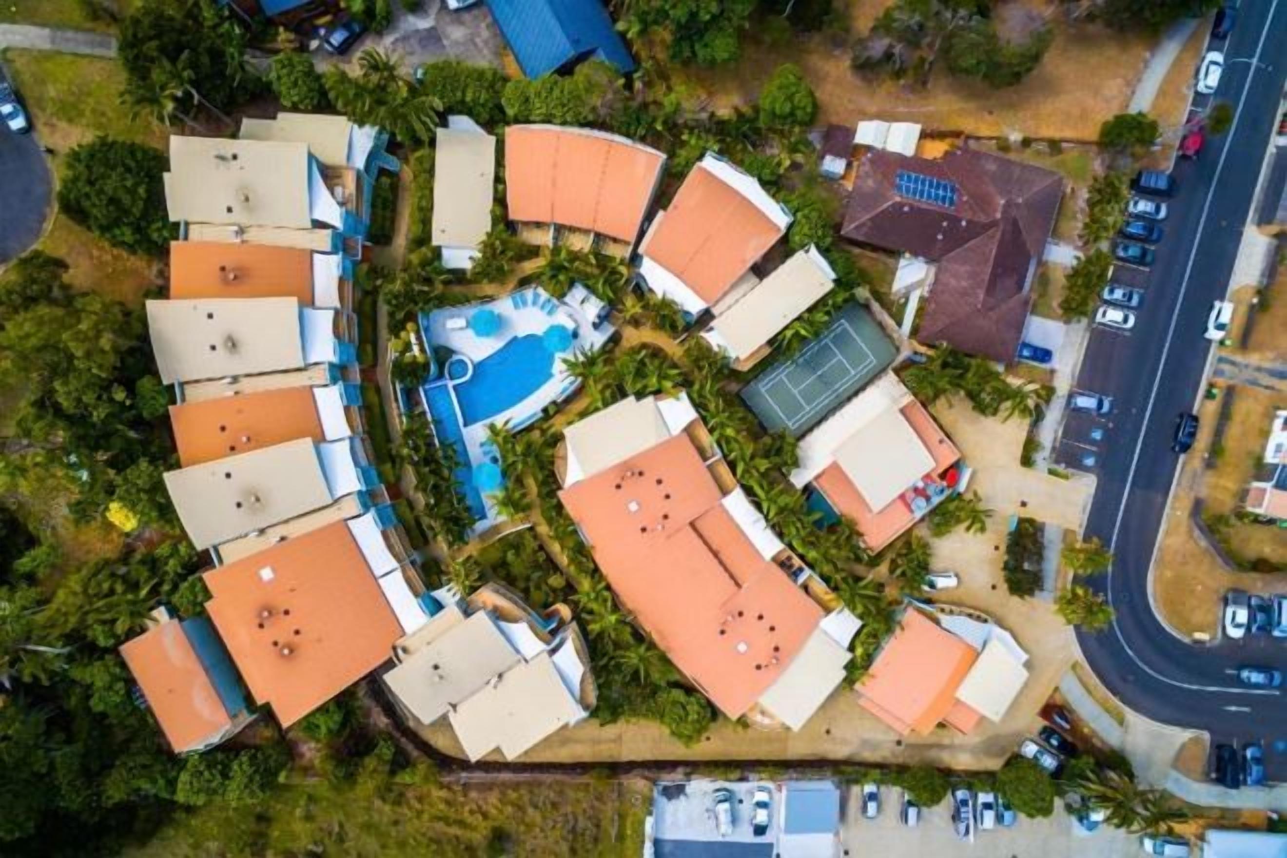 An aerial view of a resort with multiple buildings, a swimming pool, and a tennis court.