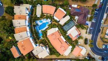 An aerial view of a resort with multiple buildings, a swimming pool, and a tennis court.