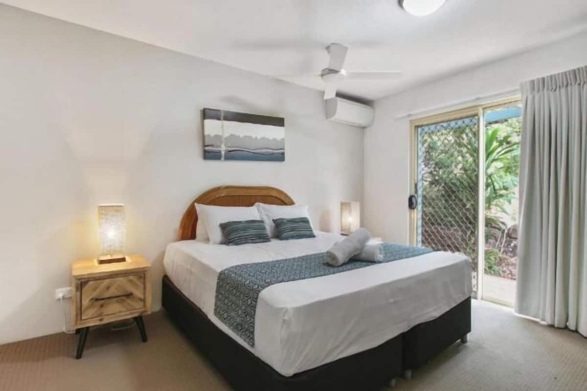 A bedroom with a bed, bedside table, and a ceiling fan.