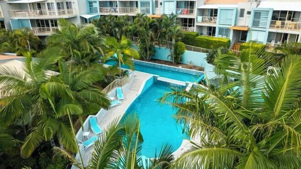 A resort with multiple buildings, a swimming pool, and palm trees. - Lennox Beach Resort (Lennox Head)