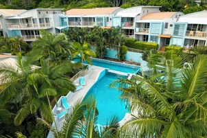 Un resort con varias construcciones, piscina y palmeras.