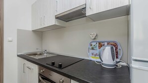 Une cuisine avec des meubles blancs, un plan de travail noir, une machine à café et un grille-pain.