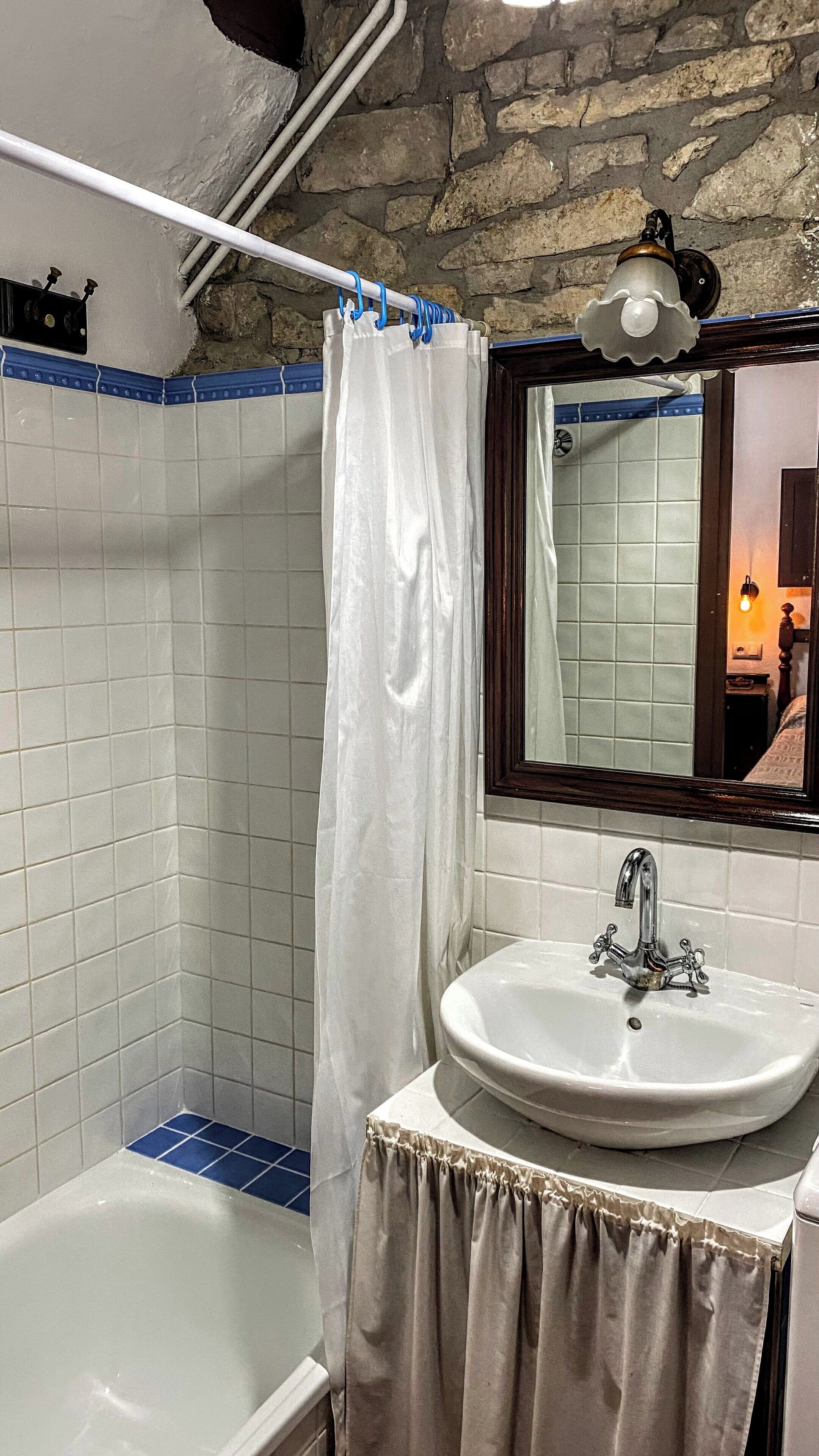 Une salle de bain avec une baignoire, un lavabo blanc, un miroir et un rideau de douche.