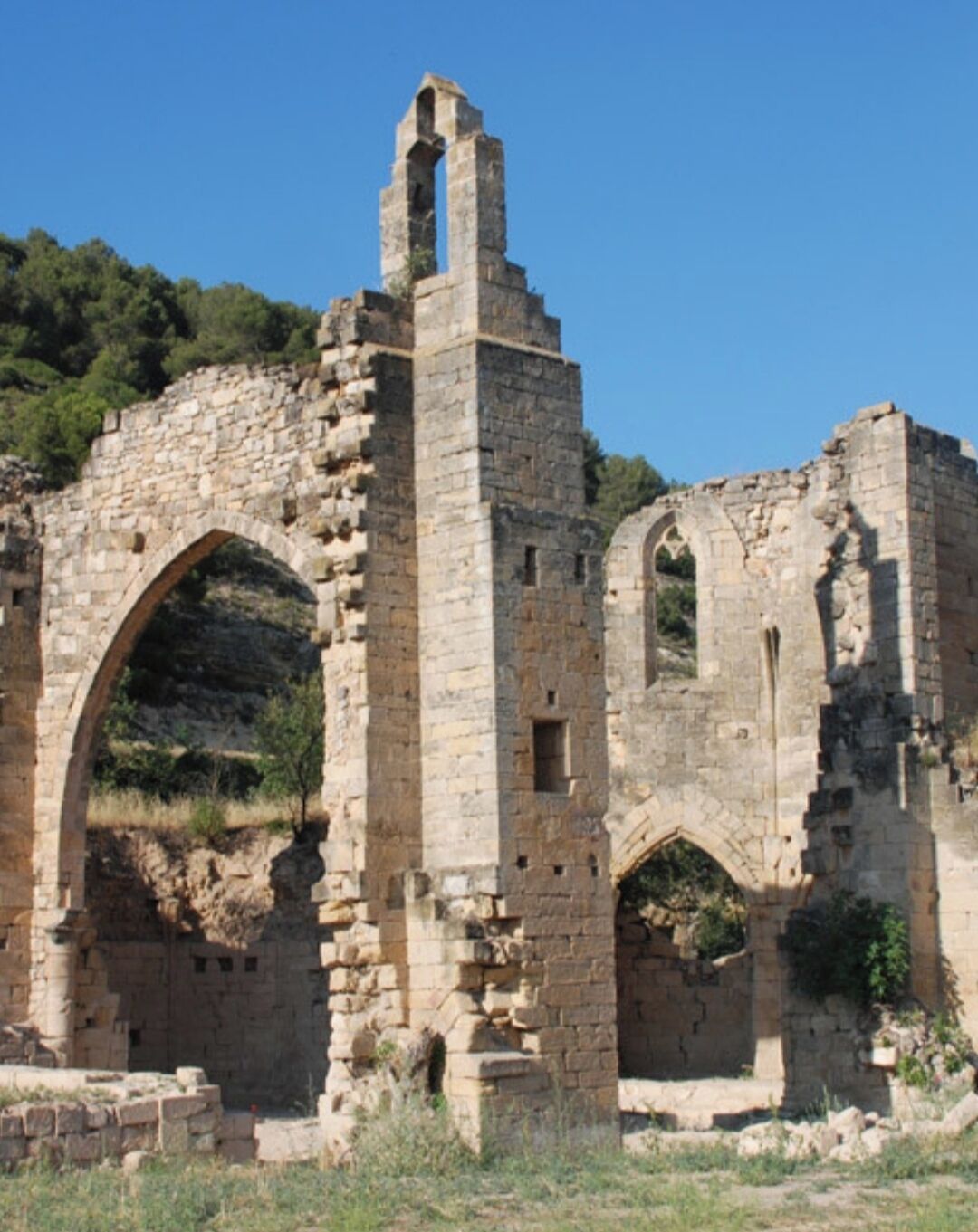 Vestiges d’anciens bâtiments en pierre, avec des structures en arc et une haute tour étroite.