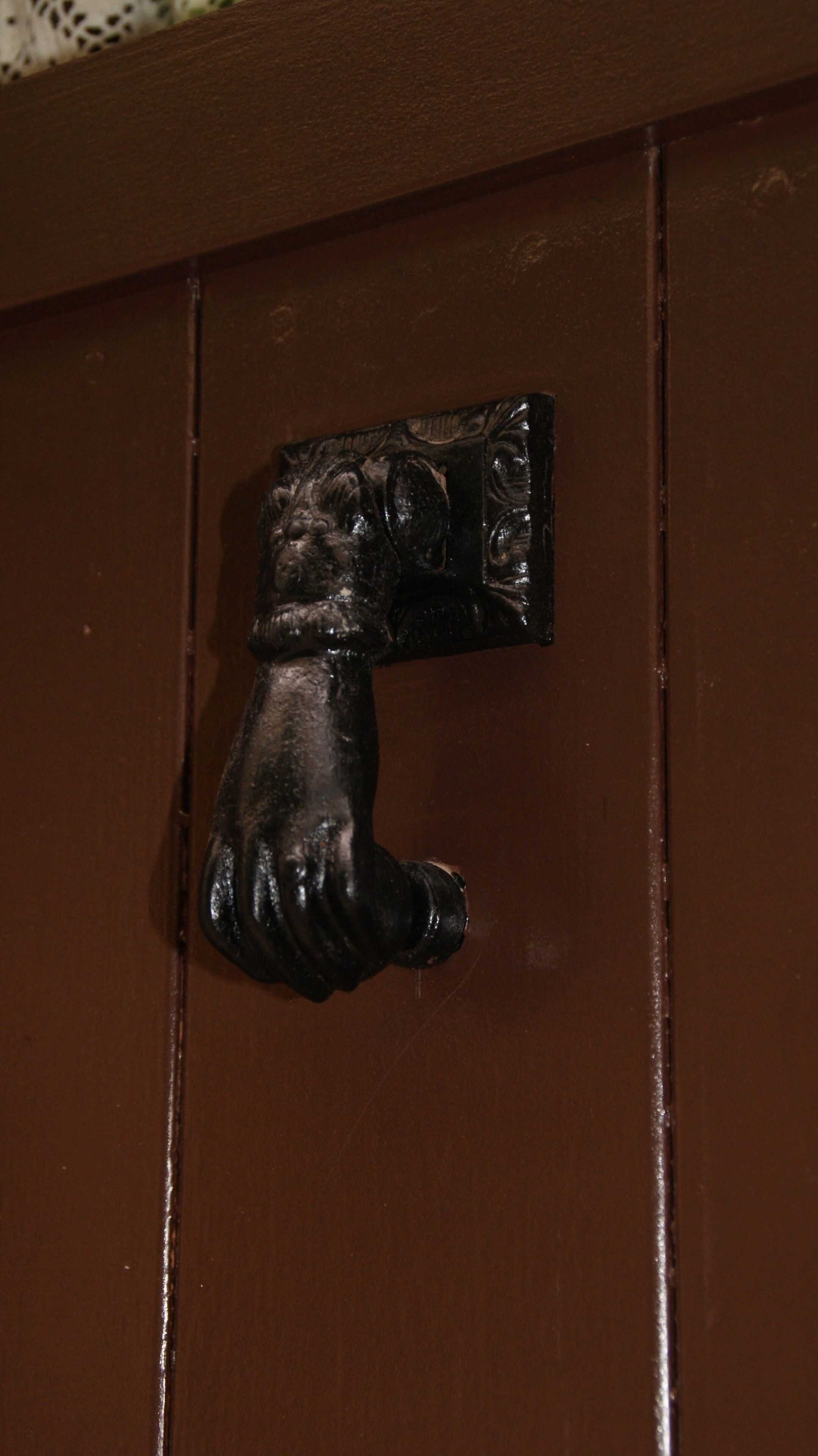 A brown door with a black, dog-shaped handle.