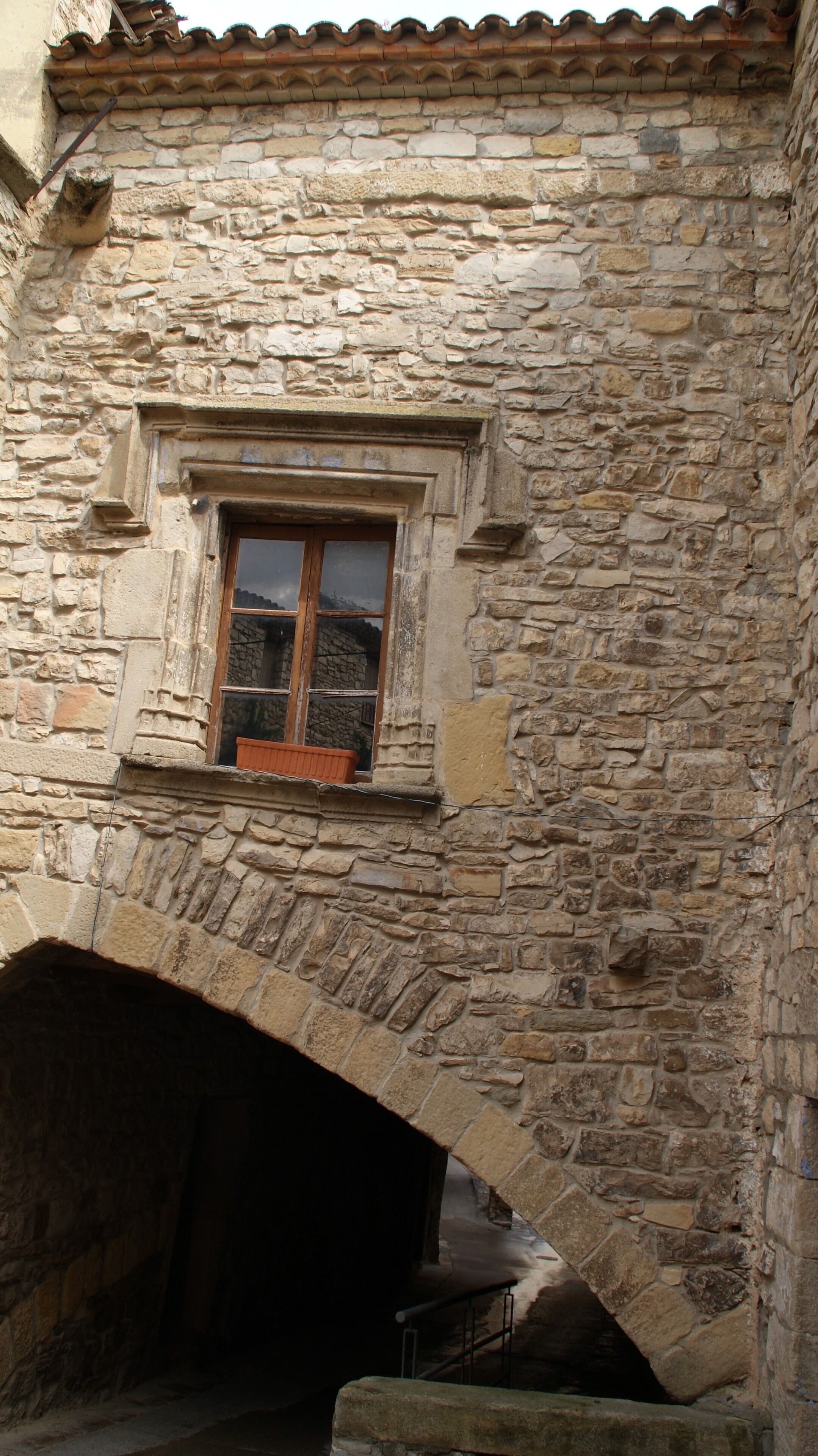 A stone building with a window and an archway.