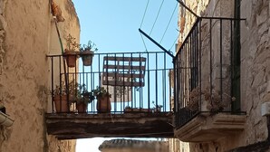 A narrow alleyway with a balcony on the left and a building on the right. - CAN PINÓS DE GUIMERÀ  (Guimerà)