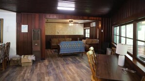 A room with wooden paneling, a sofa, a dining table with chairs, and a window. - "The Lodge" River Access 2 Kitchens Dines 18 ppl

 (Garberville)