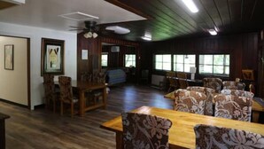 A spacious room with wooden flooring, a dining table with chairs, and a ceiling fan. - "The Lodge" River Access 2 Kitchens Dines 18 ppl

 (Garberville)