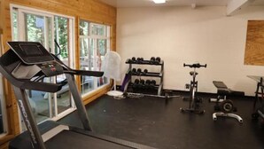 Ein Fitnessstudio mit Laufband, Kurzhanteln und Krafttrainingsgeräten.