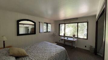 Un dormitorio con cama, escritorio, espejo y ventana.