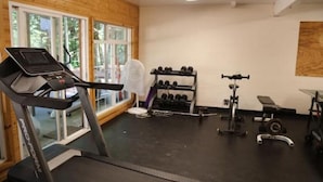Ein Fitnessstudio mit Laufband, Kurzhanteln und Krafttrainingsgeräten.