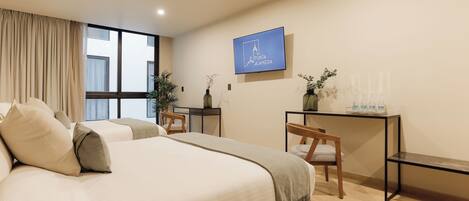 A modern hotel room with a large bed, a desk, and a television displaying 'Punta Alamedas'.