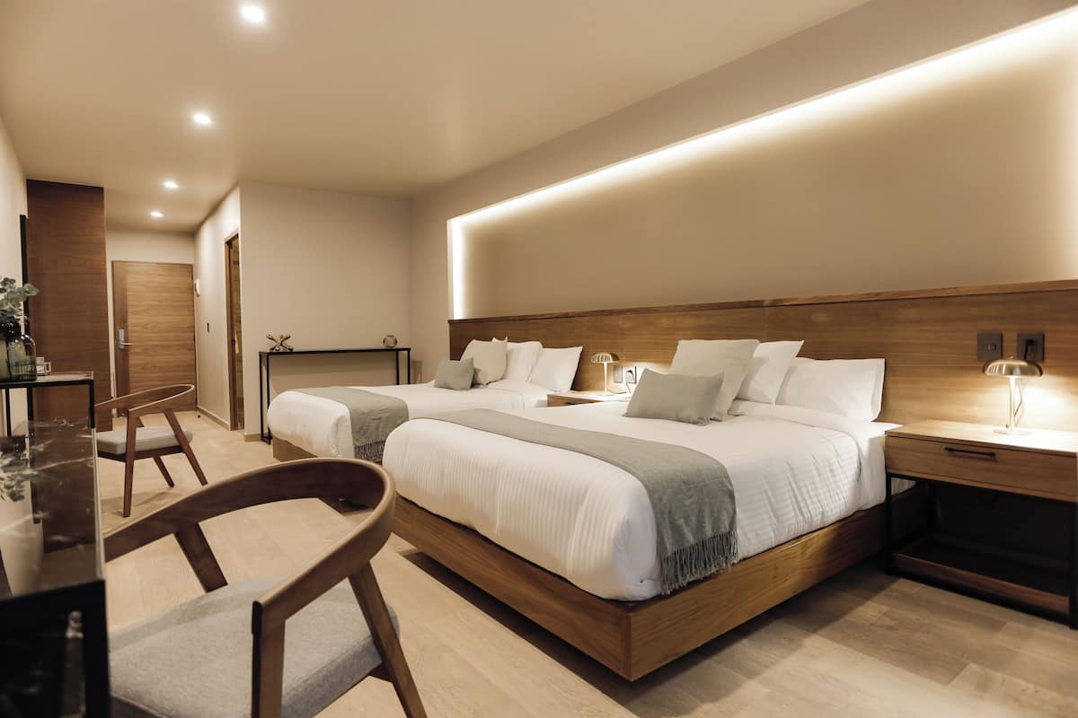 A modern hotel room with a large bed, bedside tables, a desk, and a chair.