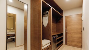 Un dressing avec des portes en bois, un miroir et une tringle pour suspendre les vêtements.