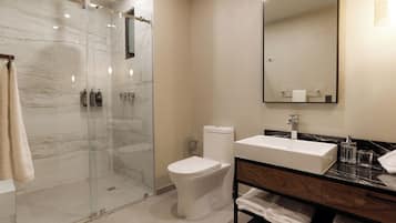 A modern bathroom with a glass-enclosed shower, a white toilet, a sink with a marble countertop, and a mirror above the sink.