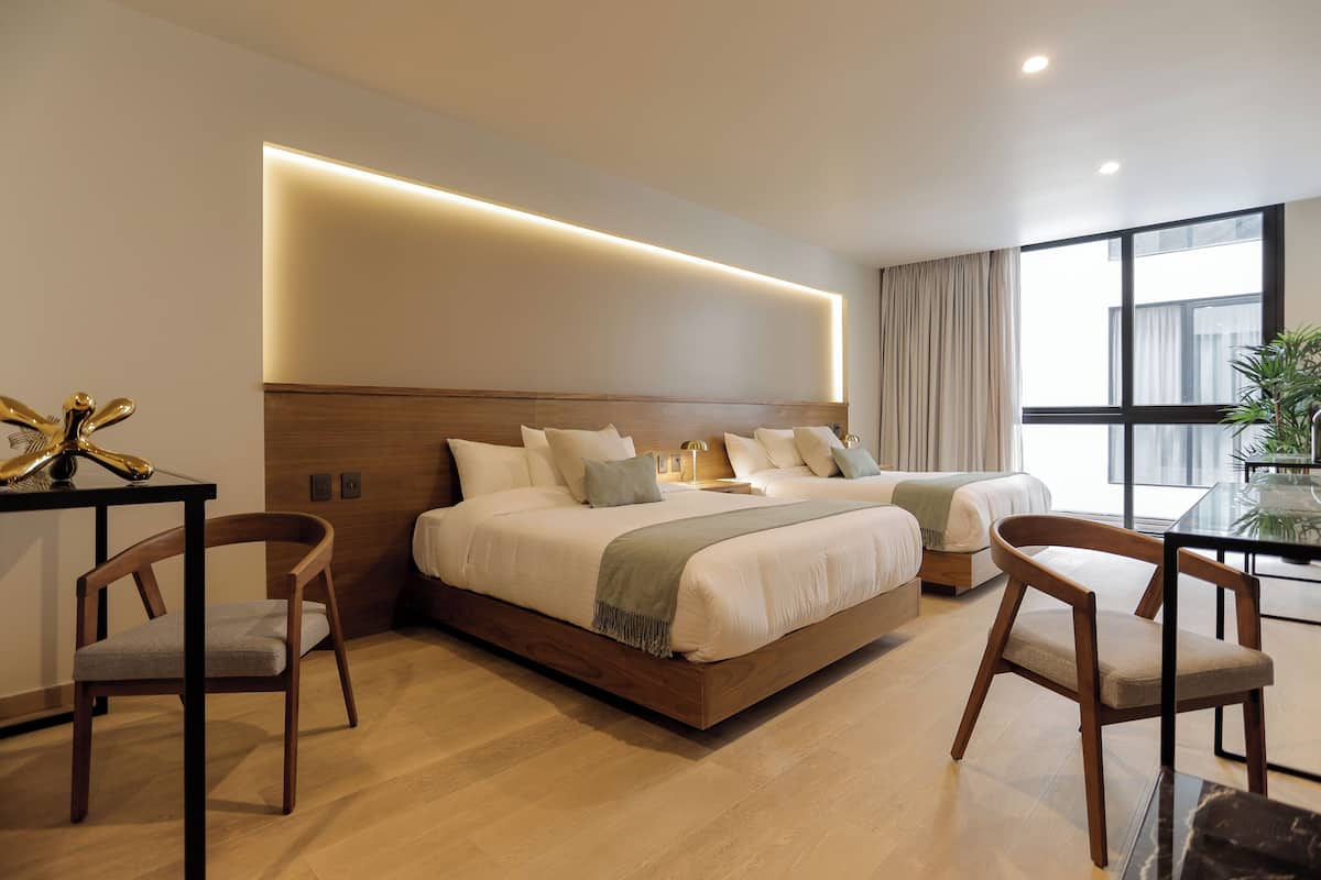 A modern hotel room with a large bed, two bedside tables, a desk, and a chair.