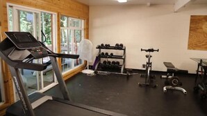 Ein Fitnessstudio mit Laufband, Kurzhanteln und Krafttrainingsgeräten.