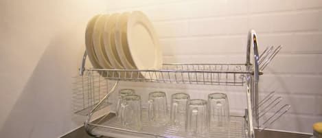 Un escurreplatos metálico con platos y vasos sobre una encimera.