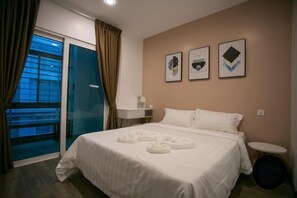 A hotel room with a bed, a small bedside table, a chair, a window with curtains, and artwork on the wall. - Paradise Suite at KK Times Square, Beside Imago (Kota Kinabalu)