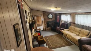 Una sala de estar acogedora con un sofá, sillones, una chimenea y un reloj en la pared.