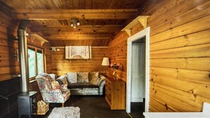 A cozy cabin interior with a fireplace, a sofa, and a lamp. - Beautiful 1-bed Secluded Cabin, With bar & Fire (Godstone)