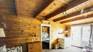 A cozy cabin interior with wooden walls, a bed, a dresser, and a small kitchenette. - Beautiful 1-bed Secluded Cabin, With bar & Fire (Godstone)