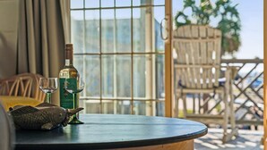 Une table avec une bouteille et des verres, un salière en forme de poisson, et une vue sur l’extérieur par une fenêtre.