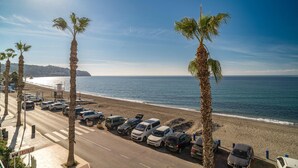A coastal road with parked cars, palm trees, and a beach in the background. - Stunning apartment in Almuñecar (Almuñecar)