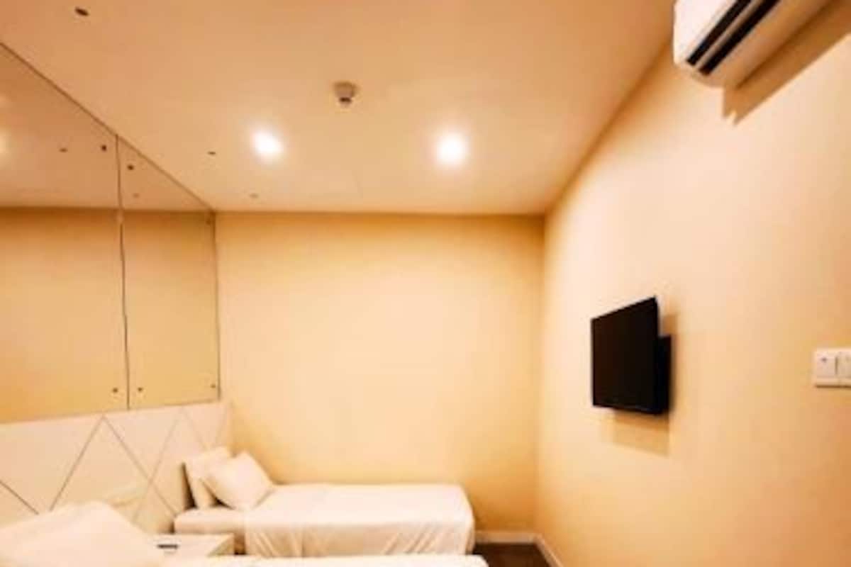 Ein Hotelzimmer mit zwei Betten, einem Flachbildfernseher und einer Klimaanlage.
