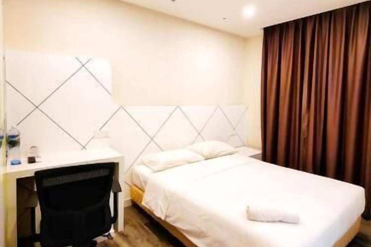 Quarto de hotel com cama, escrivaninha e cadeira.