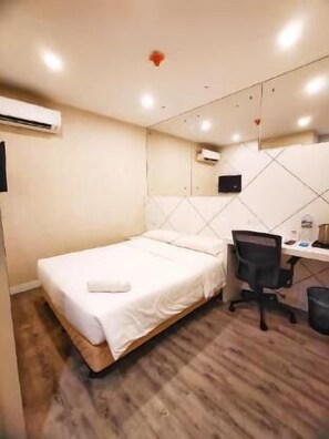 A bedroom with a bed, a desk, a chair, and an air conditioning unit. - Capital Express (Kota Kinabalu)