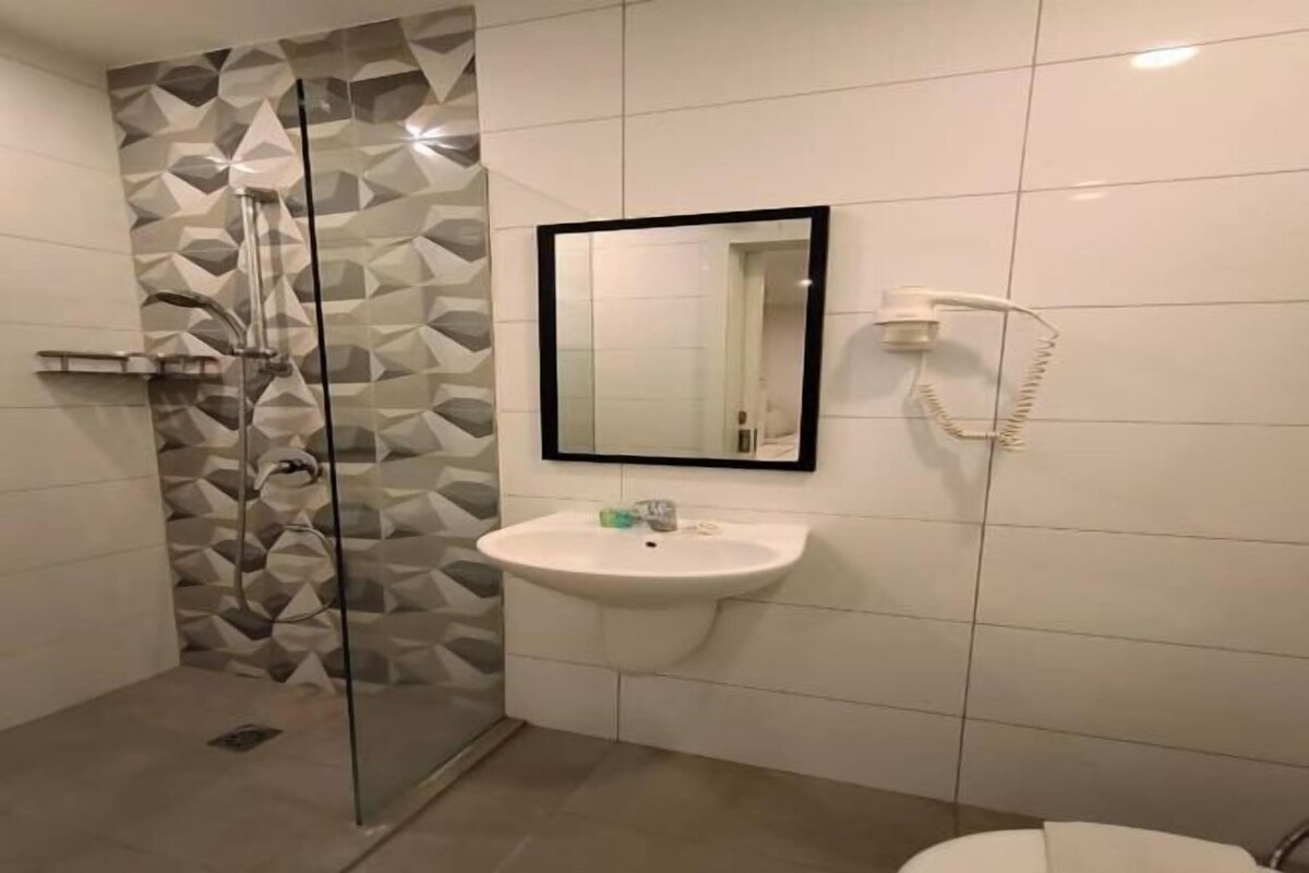 A bathroom with a glass shower enclosure, a sink with a mirror above it, and a toilet.