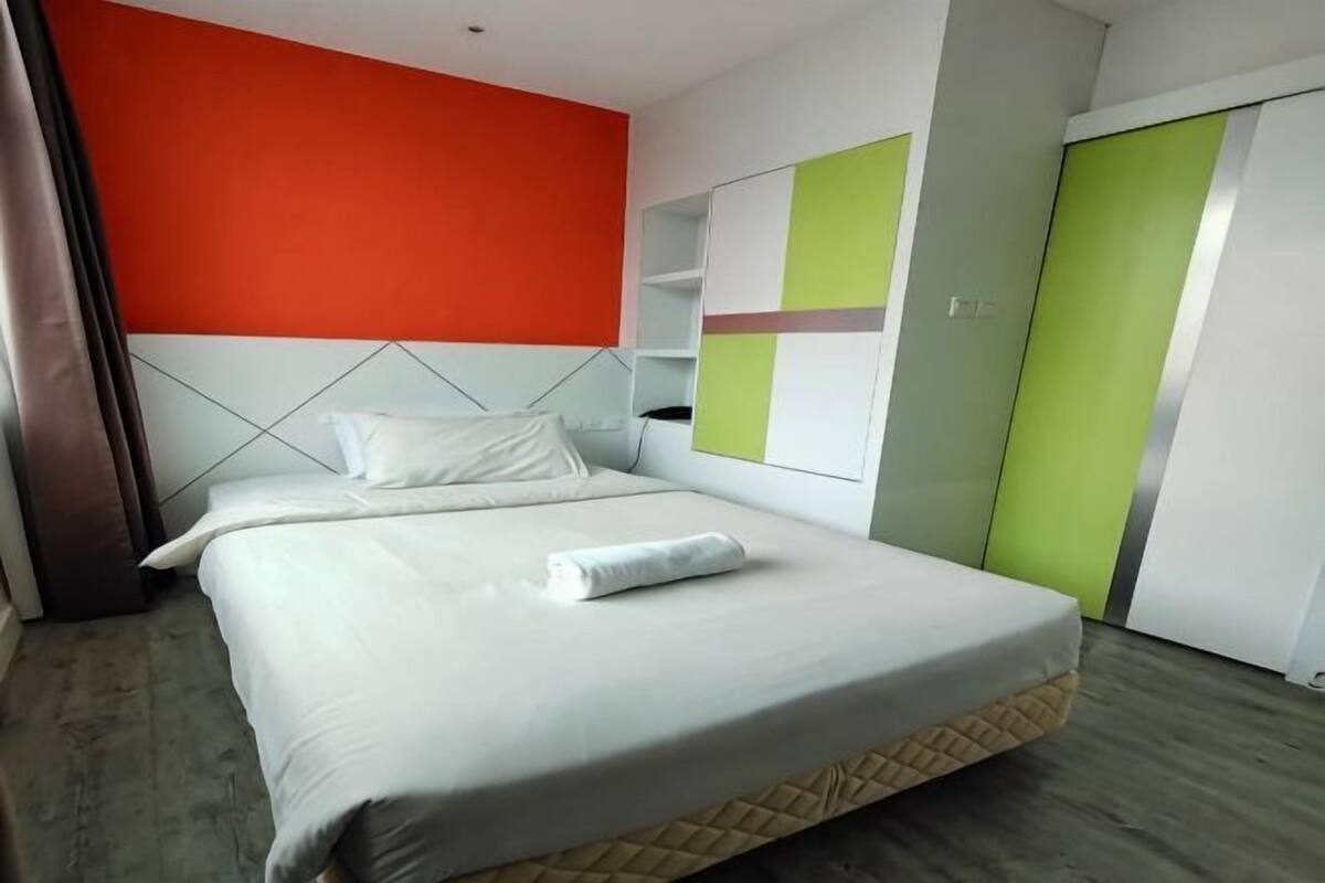 Quarto de hotel com cama, cabeceira, guarda-roupa e espelho.