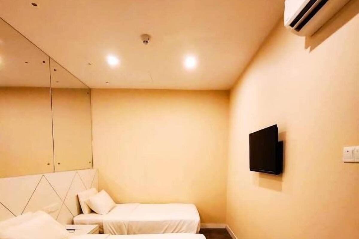 Quarto de hotel com duas camas, uma televisão montada e um aparelho de ar condicionado.