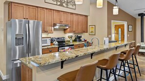 A modern kitchen with wooden cabinets, stainless steel appliances, a granite countertop, and bar stools. - Secluded Yurt Hideaway 10 min to Table Rock (cleveland)