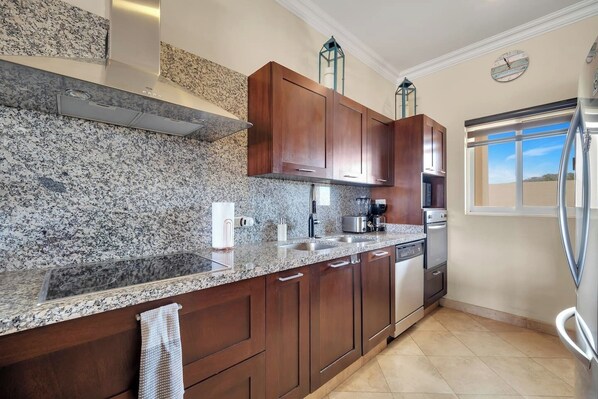 A kitchen with granite countertops, wooden cabinets, stainless steel appliances, and a window with a view. - Relax in the Best Location Cabo! (Cabo San Lucas)