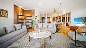 A modern living room with a sofa, coffee table, and dining area.