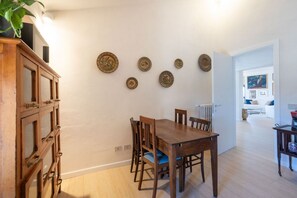 A dining area with a wooden table and chairs, a cabinet with glass doors, and a wall with decorative plates.