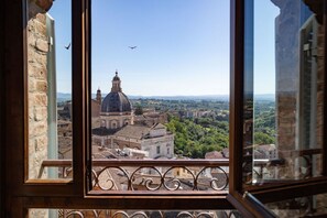 Vista desde una ventana con barandilla metálica, sobre un paisaje urbano con edificios históricos y una estructura abovedada destacada.