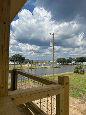 Eine Holzterrasse mit Blick auf einen See, Boote und einen bewölkten Himmel.