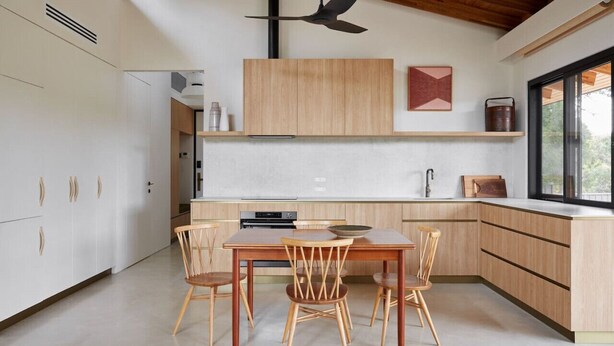 A modern kitchen with wooden cabinets, a dining table with chairs, a ceiling fan, and a window providing natural light. - Ukiyo House “The Floating World” (Port Willunga)