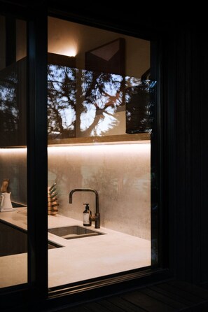 A modern bathroom with a large window, a sink, and a faucet.