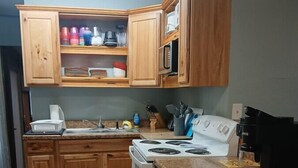 A kitchen with wooden cabinets, a white stove, and a microwave. - Fun Cabin in the Woods (Longdale)