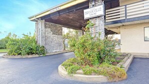 A hotel entrance with a stone facade, a covered parking area, and a sign reading "Brookville Inn". - Brookville Inn By OYO Near Dayton International Airport (Brookville)
