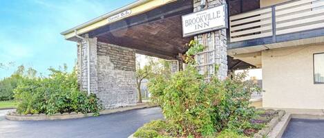 A hotel entrance with a stone facade, a covered parking area, and a sign reading "Brookville Inn".