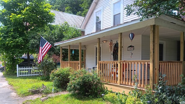 Une maison avec un porche, un drapeau et une boîte aux lettres.