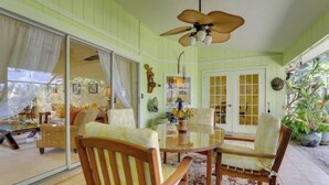 A room with a glass table, wooden chairs, a ceiling fan, and a view through a sliding glass door. - Long-term discount! Spacious 3BR Home With Tropical Garden & Koi Pond in Lanai (Punta Gorda)
