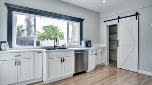 Una cocina moderna con armarios blancos, un ventanal grande y una puerta corredera estilo granja.