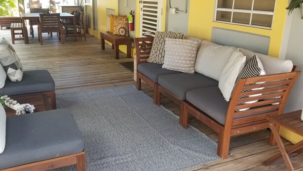 Una terraza de madera con un sofá, sillas y una pequeña mesa.